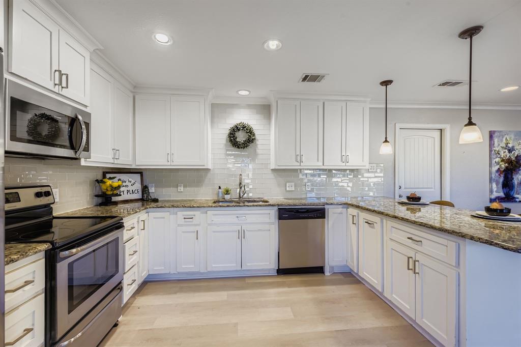 2801 Fairbrook Street Irving, TX 75062 - Photo 11 of 23 a large kitchen with stainless steel appliances granite countertop a stove a sink dishwasher and a microwave oven with white cabinets