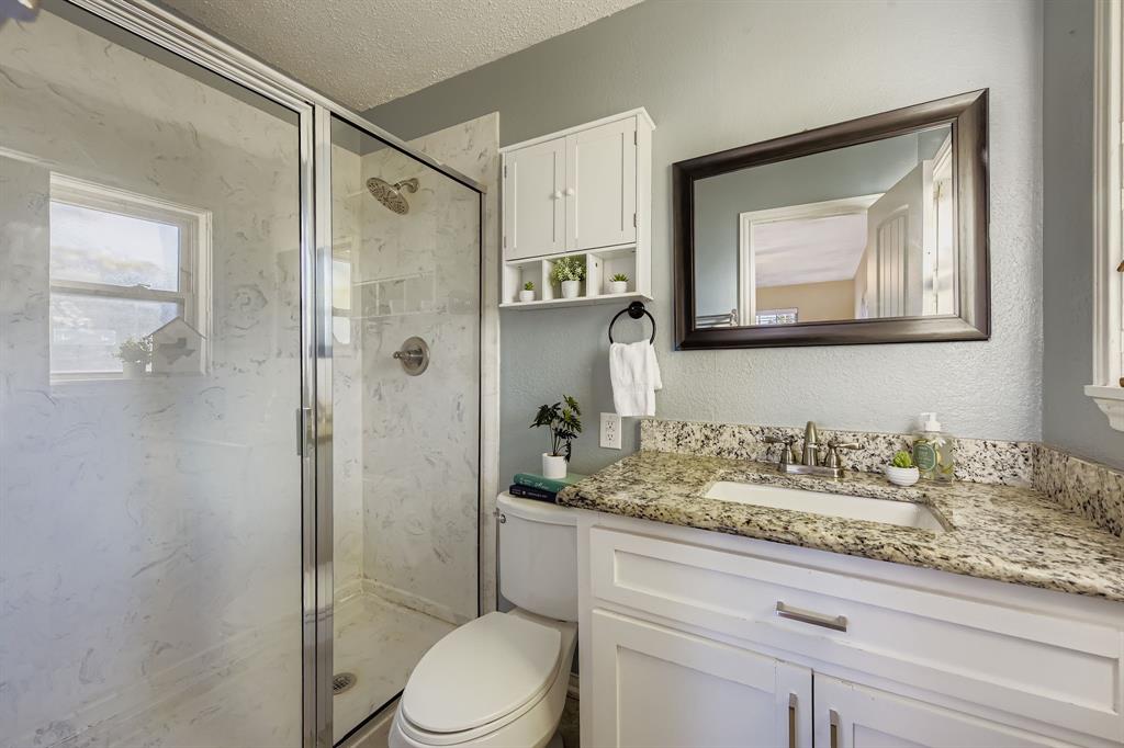 2801 Fairbrook Street Irving, TX 75062 - Photo 16 of 23 a bathroom with a granite countertop sink a toilet and shower
