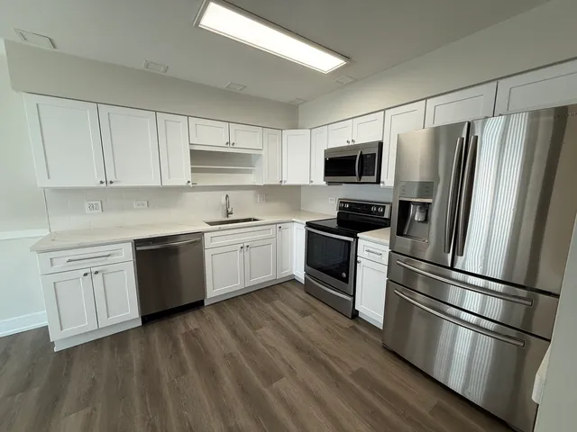 a kitchen with a refrigerator cabinets and wooden floor