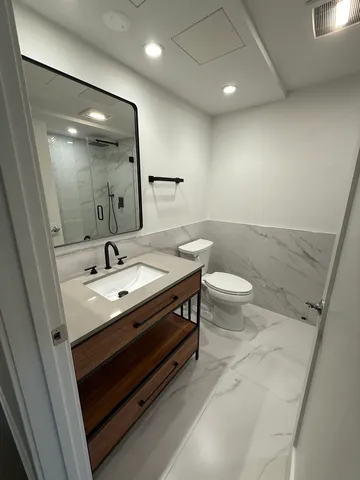 a bathroom with a sink a toilet a mirror and shower
