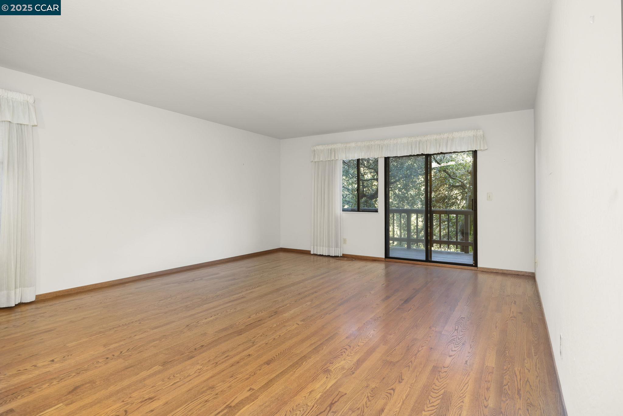 1383 Alvarado Road Berkeley, CA 94705 - Photo 19 of 47 a view of an empty room with wooden floor and a window