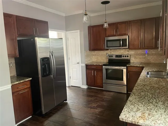 a kitchen with stainless steel appliances granite countertop a refrigerator a stove top oven a sink and dishwasher