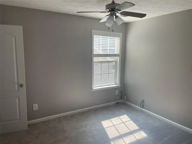 an empty room with windows and fan