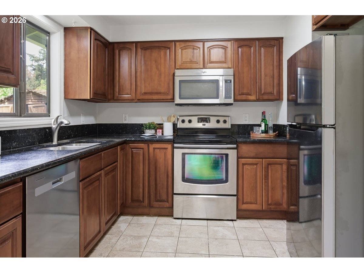 2137 Southeast 130th Avenue Portland, OR 97233 - Photo 5 of 14 a kitchen with stainless steel appliances granite countertop a stove a sink dishwasher a refrigerator and a microwave