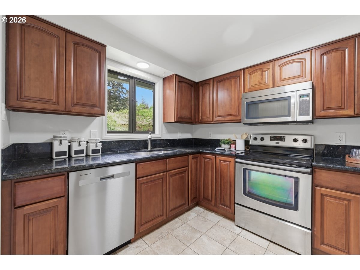 2137 Southeast 130th Avenue Portland, OR 97233 - Photo 6 of 14 a kitchen with stainless steel appliances granite countertop wooden cabinets a stove top oven a sink and dishwasher