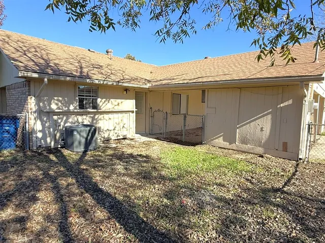 a view of a house with a large tree and wooden fence