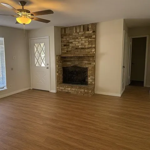 a view of an empty room with a fireplace and a window