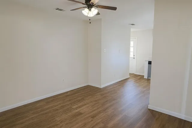 a view of a room with wooden floor and a ceiling fan