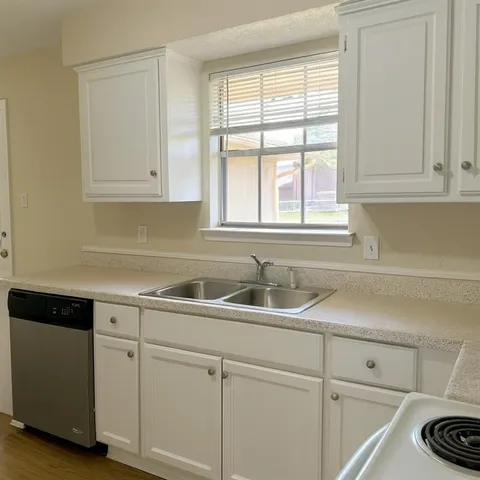a kitchen with white cabinets and a window