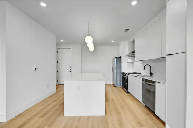 a kitchen with cabinets stainless steel appliances and a window