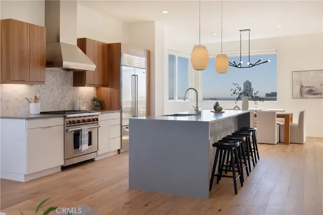 a kitchen with kitchen island granite countertop a stove a sink a dining table and chairs with wooden floor