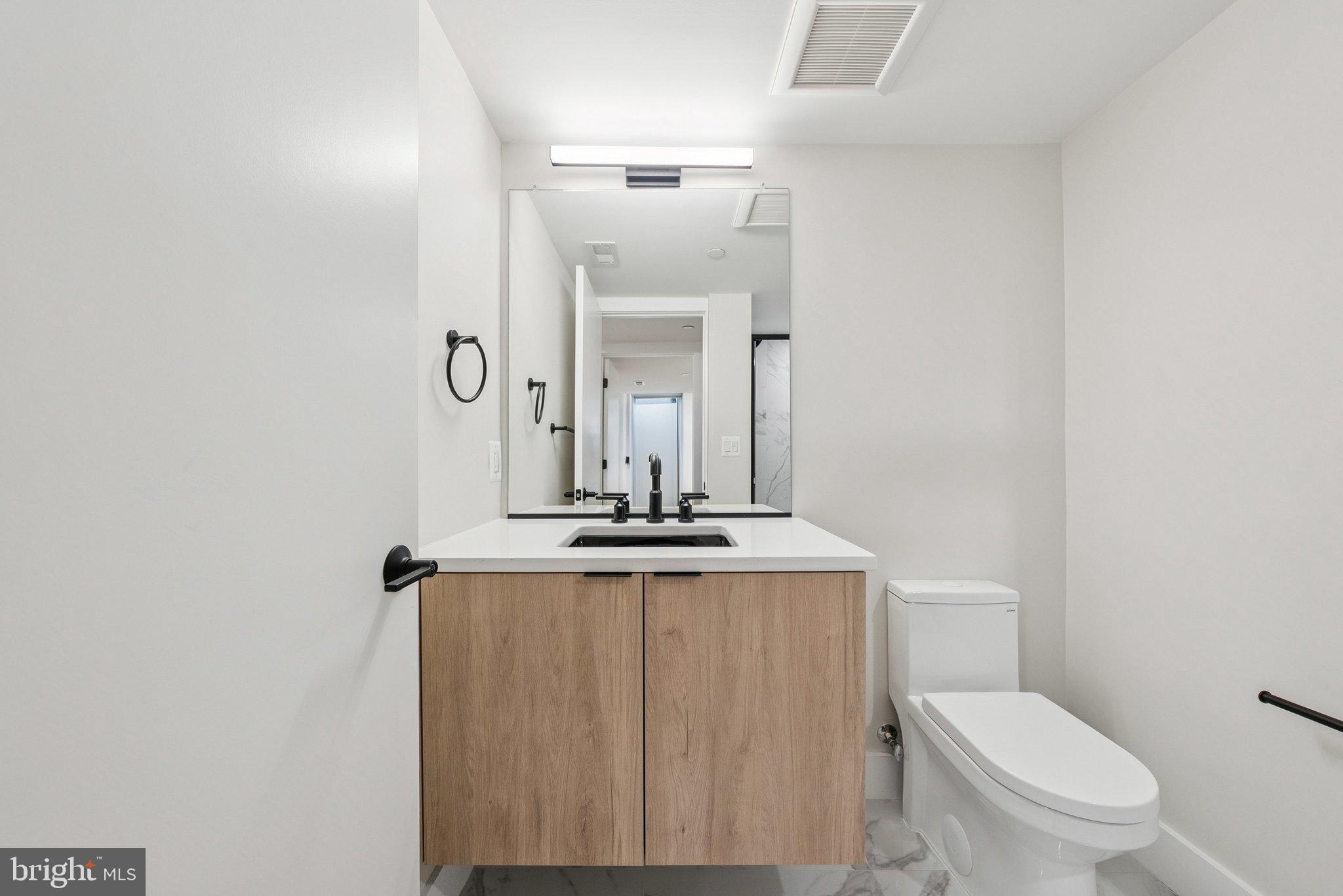 2134 Wisconsin Avenue Northwest, Unit 1 Washington, DC 20007 - Photo 19 of 32 a bathroom with a granite countertop sink mirror vanity and toilet