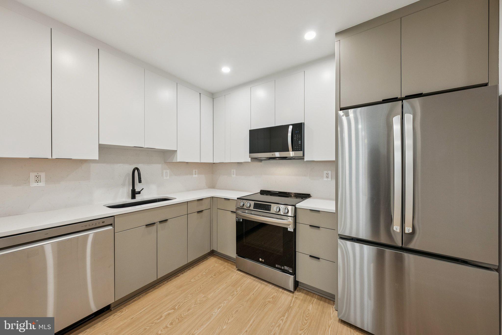 2134 Wisconsin Avenue Northwest, Unit 1 Washington, DC 20007 - Photo 4 of 32 a kitchen with white cabinets stainless steel appliances and wooden floor
