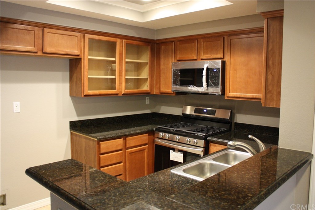 a kitchen with granite countertop a stove a sink and a microwave