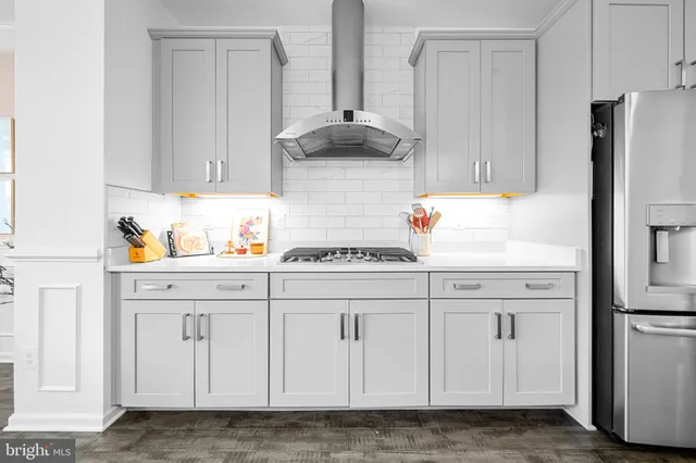 a living room with couches and kitchen view with wooden floor