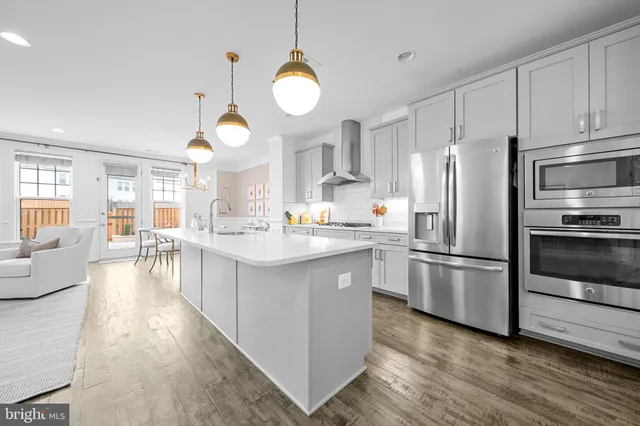 a large kitchen with stainless steel appliances kitchen island granite countertop a sink and dishwasher a refrigerator with wooden floor