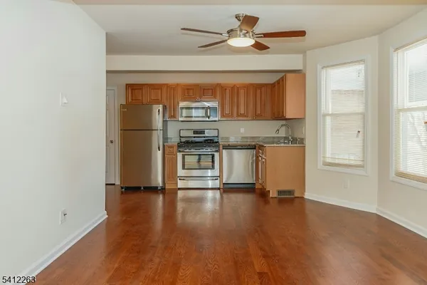 a kitchen with stainless steel appliances a stove a refrigerator and a hard wood floor