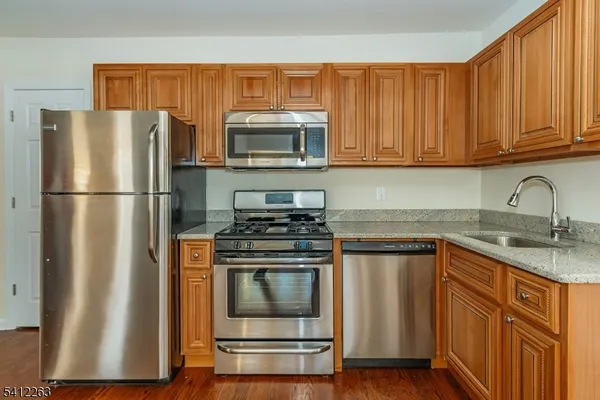 a kitchen with stainless steel appliances granite countertop a refrigerator stove and sink
