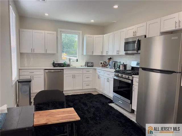 a kitchen with granite countertop a refrigerator stove top oven and sink