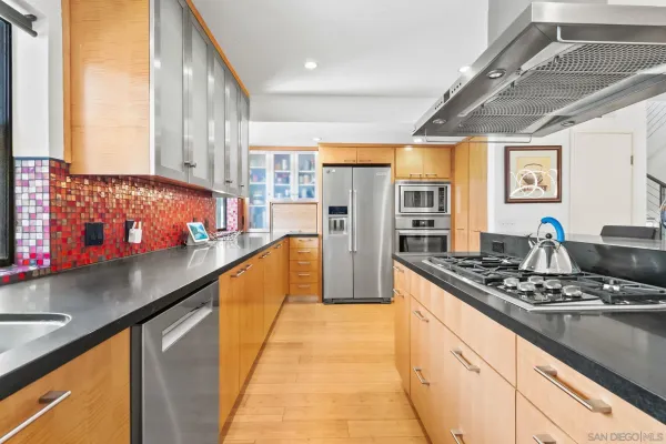 a room with stainless steel appliances kitchen island granite countertop dining table chairs and a large window