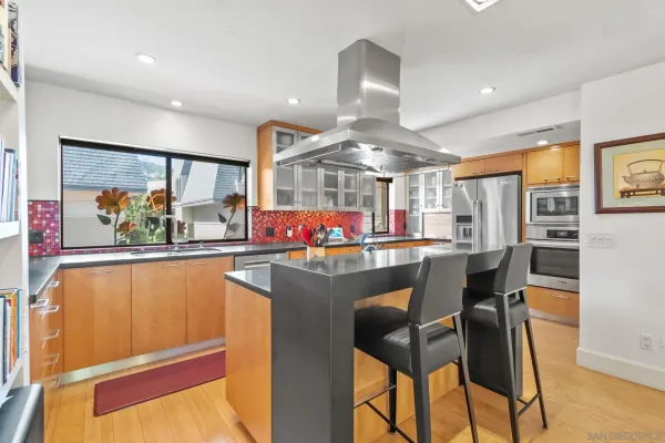 a kitchen with stainless steel appliances granite countertop a dining table chairs and a refrigerator