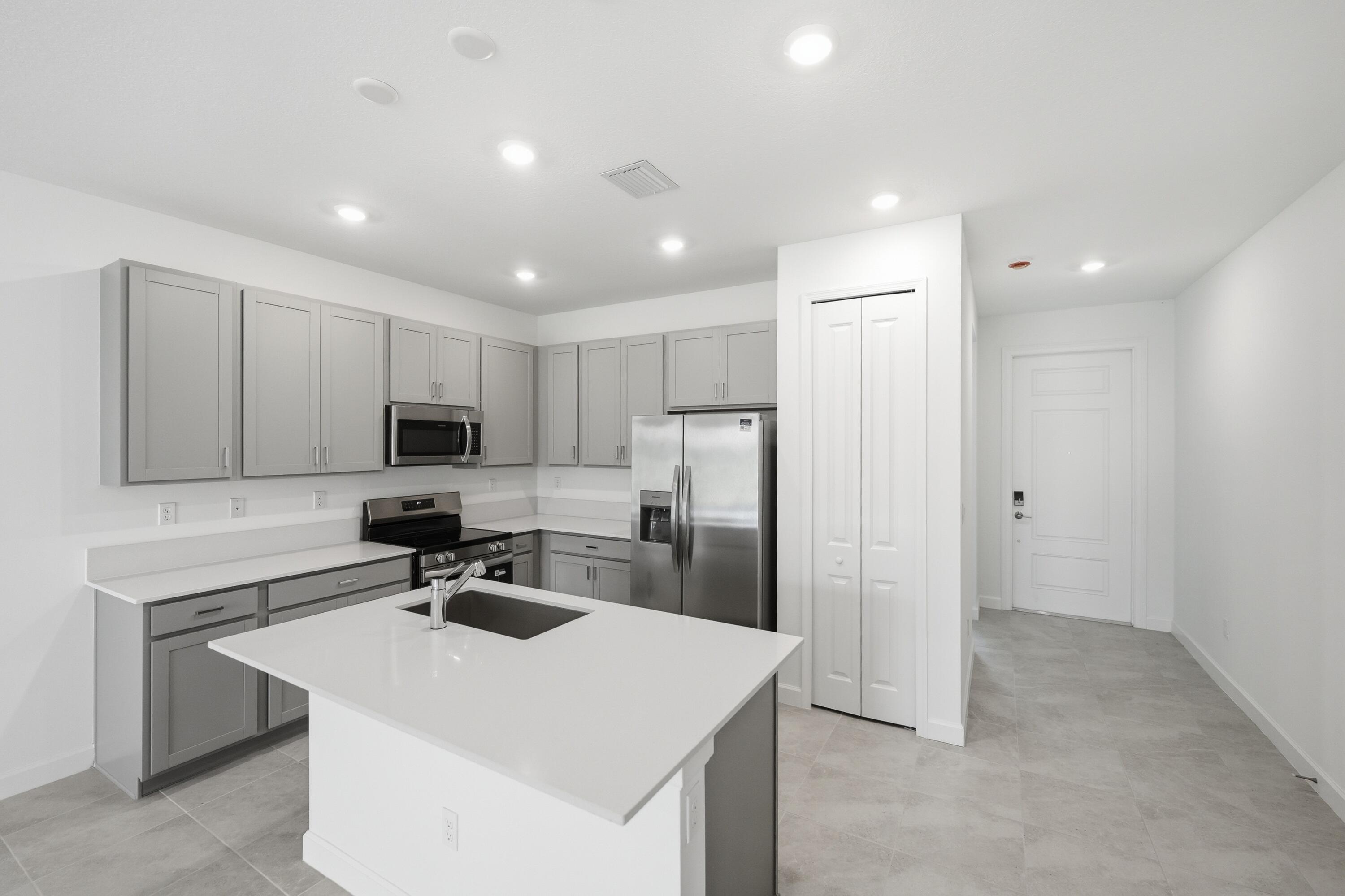 3736 Harborside Avenue Fort Pierce, FL 34946 - Photo 2 of 16 a kitchen that has a sink a refrigerator and a stove top oven with white countertops