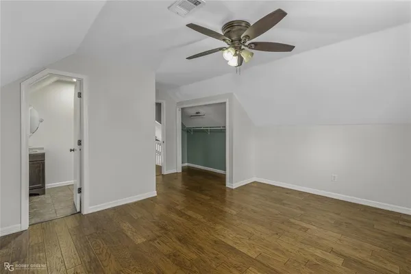 an empty room with wooden floor and a ceiling fan