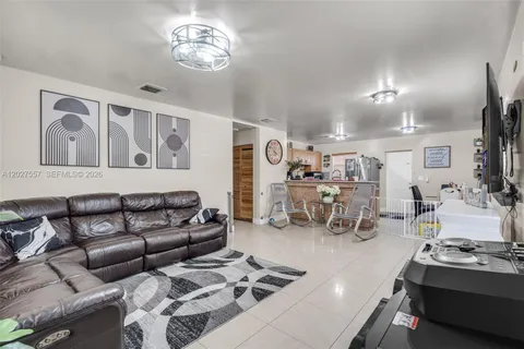 a living room with furniture a chandelier and kitchen view