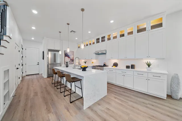 a large white kitchen with lots of counter space wooden floor and appliances