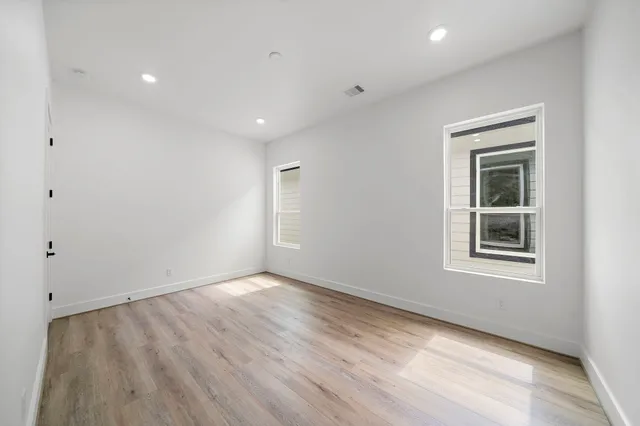 an empty room with wooden floor and windows