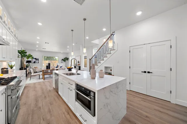 a large kitchen with stainless steel appliances granite countertop a lot of counter space and a wooden floor