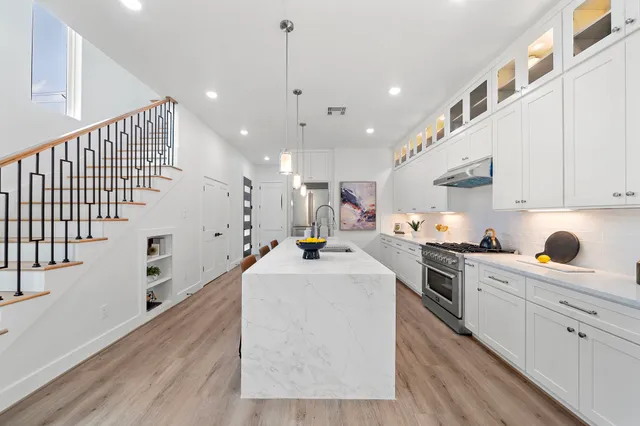 a large white kitchen with lots of counter top space wooden floor and stainless steel appliances