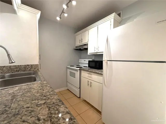 a kitchen with a refrigerator and a stove top oven