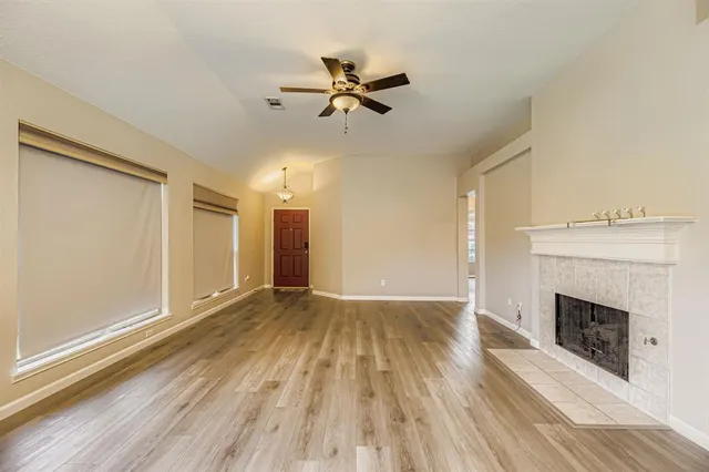 a view of an empty room with a window and wooden floor