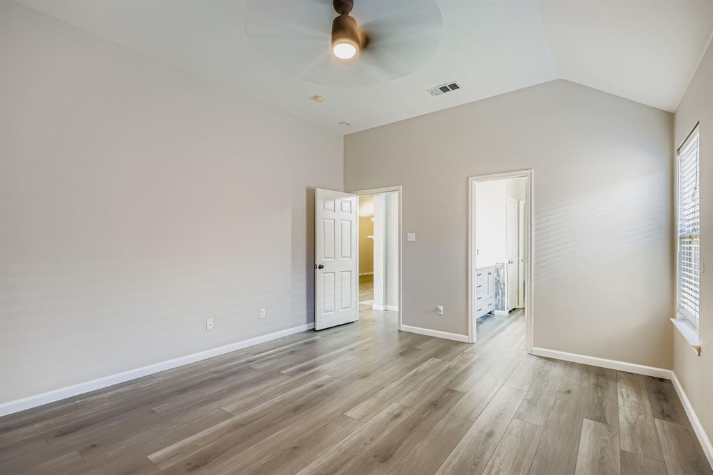 5452 Buckskin Drive The Colony, TX 75056 - Photo 21 of 31 Unfurnished primary bedroom featuring light wood finished floors, ceiling fan, ensuite bath, and vaulted ceiling