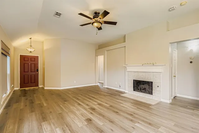 a view of a livingroom with a fireplace a ceiling fan and hardwood floor