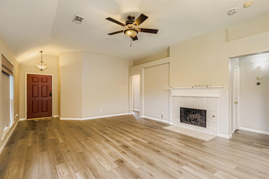5452 Buckskin Drive The Colony, TX 75056 - Photo 9 of 31 Unfurnished living room featuring light wood-style flooring, a ceiling fan, lofted ceiling, and a fireplace