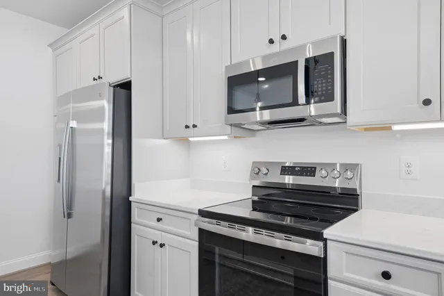 a kitchen with stainless steel appliances granite countertop white cabinets and a stove a oven with white countertops