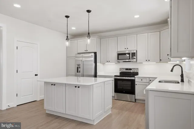 a kitchen with kitchen island a sink stainless steel appliances and cabinets