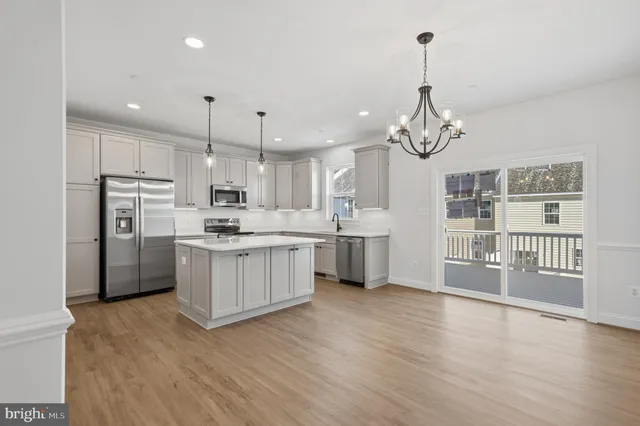 a kitchen with stainless steel appliances granite countertop a refrigerator a sink dishwasher a stove and white cabinets with wooden floor