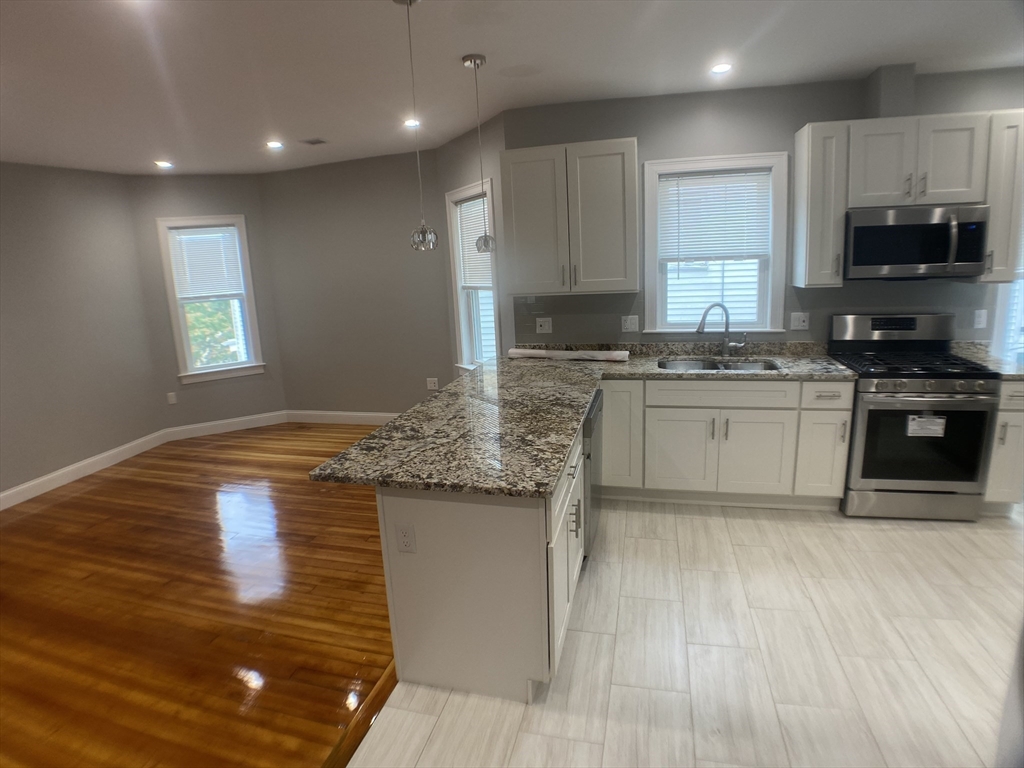 27 Juliette Street Boston, MA 02122 - Photo 8 of 37 a kitchen with stainless steel appliances granite countertop a stove a sink and a microwave