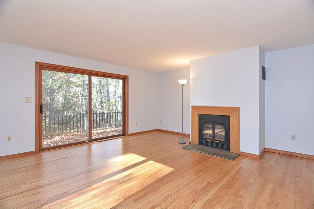 88 Townsend Road, Unit A Shirley, MA 01464 - Photo 4 of 35 an empty room with wooden floor fireplace and windows