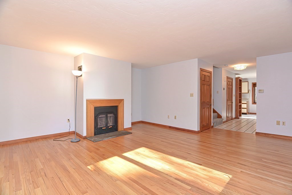 88 Townsend Road, Unit A Shirley, MA 01464 - Photo 6 of 35 a view of an empty room with wooden floor fireplace and a window