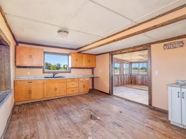 a large kitchen with stainless steel appliances wooden floor and a large window
