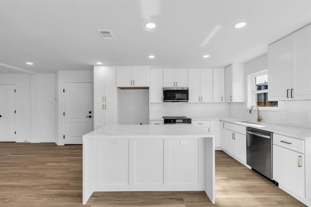 906 Thistle Circle Allen, TX 75002 - Photo 13 of 40 a kitchen with stainless steel appliances a stove top oven a sink a refrigerator white cabinets and wooden floor