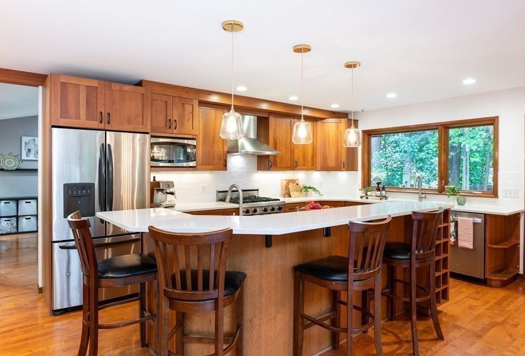 12 Rice Spring Lane Wayland, MA 01778 - Photo 12 of 37 a kitchen with stainless steel appliances granite countertop a stove a refrigerator a kitchen island a table and chairs