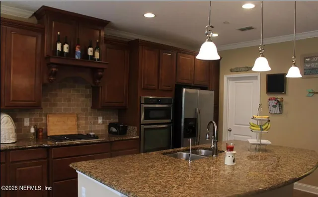 a kitchen with stainless steel appliances granite countertop a sink refrigerator and cabinets