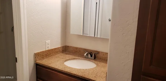 a bathroom with a granite countertop sink and a mirror