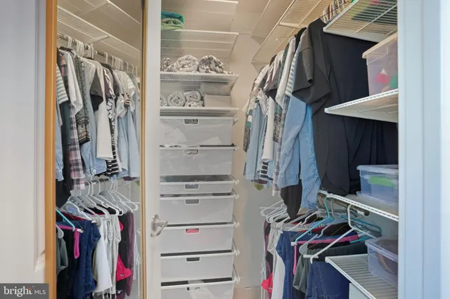 a view of walk in closet with clothes and shoes
