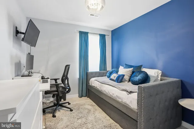 a bedroom with a bed and a computer on a desk next to a window